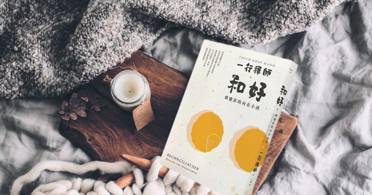一行禪師《和好：療癒你的內在小孩》書籍放在床鋪上，旁邊擺著蠟燭