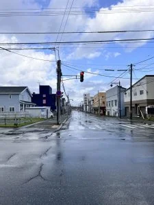 雨後的稚內街口與紅綠燈，濕潤路面映著藍天