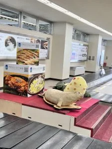 稚內機場行李輸送帶上擺著海豹造型吉祥物，後方展示當地旅遊海報
